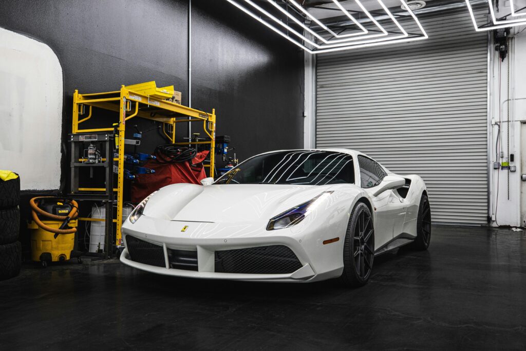 Elegant white Ferrari parked inside a sleek, modern garage setting with industrial design elements.